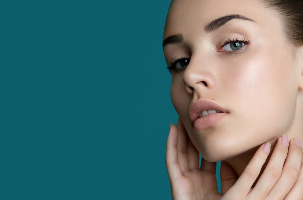 Woman admires her clear complexion and flawless skin by being proactive with cosmetic treatments.